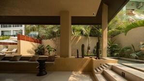 A modern outdoor lounge area with a seating arrangement, a decorative planter, and a staircase leading to an upper level.