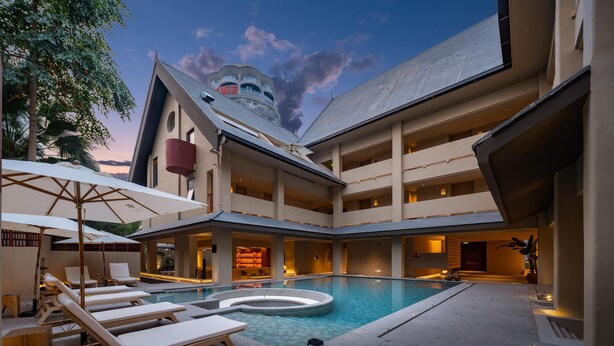A hotel with a pool, lounge chairs, and a restaurant.