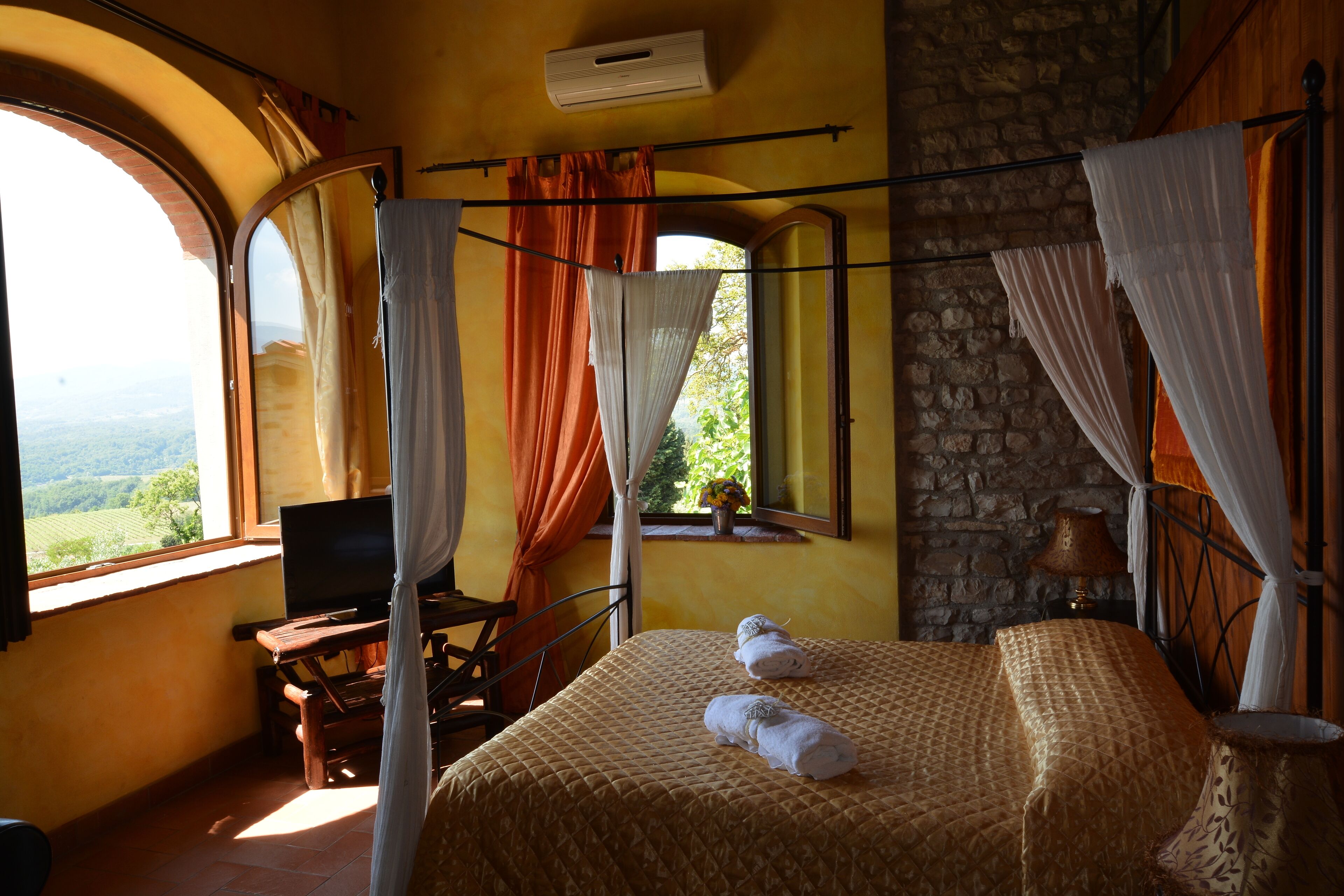 Une chambre à coucher avec un lit, un bureau, une chaise, un téléviseur et une fenêtre avec des rideaux.