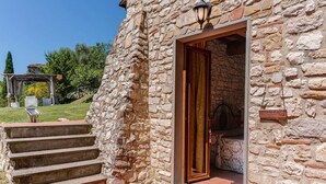 A stone building with a wooden door and steps leading to a covered area. - Dream Tuscany (Toscana)