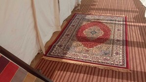 A tent with a striped carpet and a patterned rug on the floor. - Chanderi Eco Retreat (Chanderi)