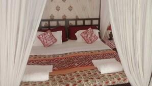 A bed with a canopy, patterned bedding, and pillows. - Chanderi Eco Retreat (Chanderi)