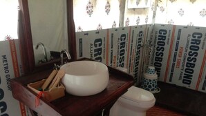 A bathroom with a white sink, a toilet, and a shower area. There are posters on the walls advertising 'CROSSBOND' and 'METRO GROUP'. - Chanderi Eco Retreat (Chanderi)