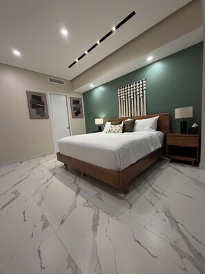 Una camera da letto moderna con un letto grande, un comodino, una lampada a parete e un elemento decorativo a parete.