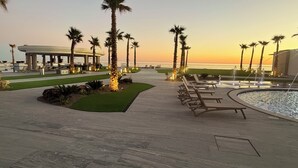 Un resort con piscina, palme e vista sul tramonto.