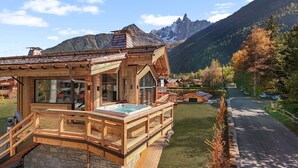 Un chalet en bois doté d’un bain à remous et offrant une vue sur les montagnes.