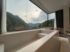 A modern living room with a large window offering a view of a mountainous landscape. - Nature Eco Designer Hotel (Zhangjiajie)