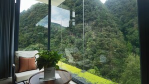 Ein modernes Zimmer mit großem Fenster mit Blick auf ein saftig grünes Tal.