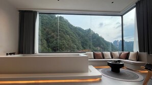 Ein modernes Wohnzimmer mit großem Fenster, einer Couch, einem Couchtisch und einer eingebauten Badewanne.