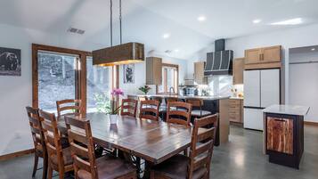 Une cuisine moderne avec des meubles en bois, un îlot central et un coin repas comprenant une grande table et des chaises.