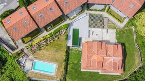 Un complejo residencial con varias edificaciones de techo rojo, una piscina y una cancha de tenis verde.