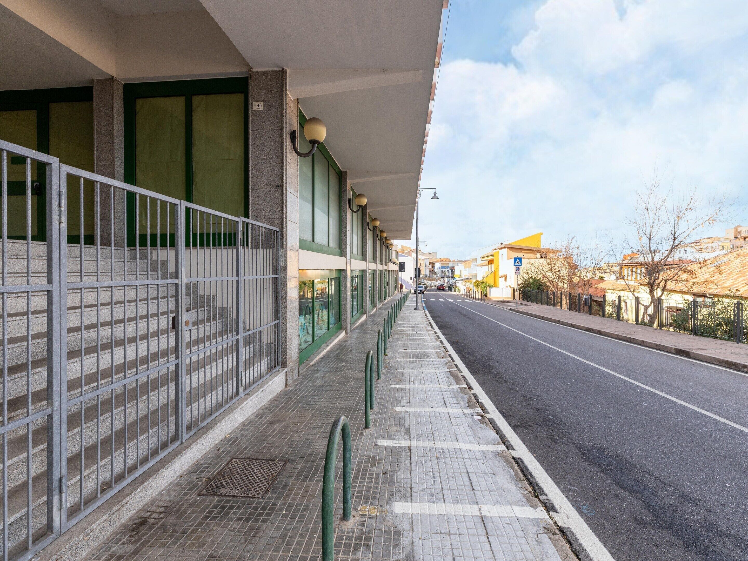 A building with a covered walkway, a gated entrance, and a clear sky.