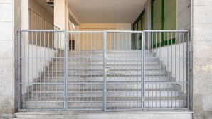 A set of concrete stairs leading to a building entrance, enclosed by a metal gate. - Aria Condizionata e Terrazza Vista Mare (Castelsardo)