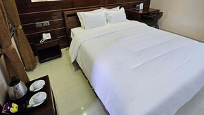 Een hotelkamer met een groot bed, een nachtkastje met een telefoon en lamp, een houten hoofdbord en een decoratief wandpaneel.