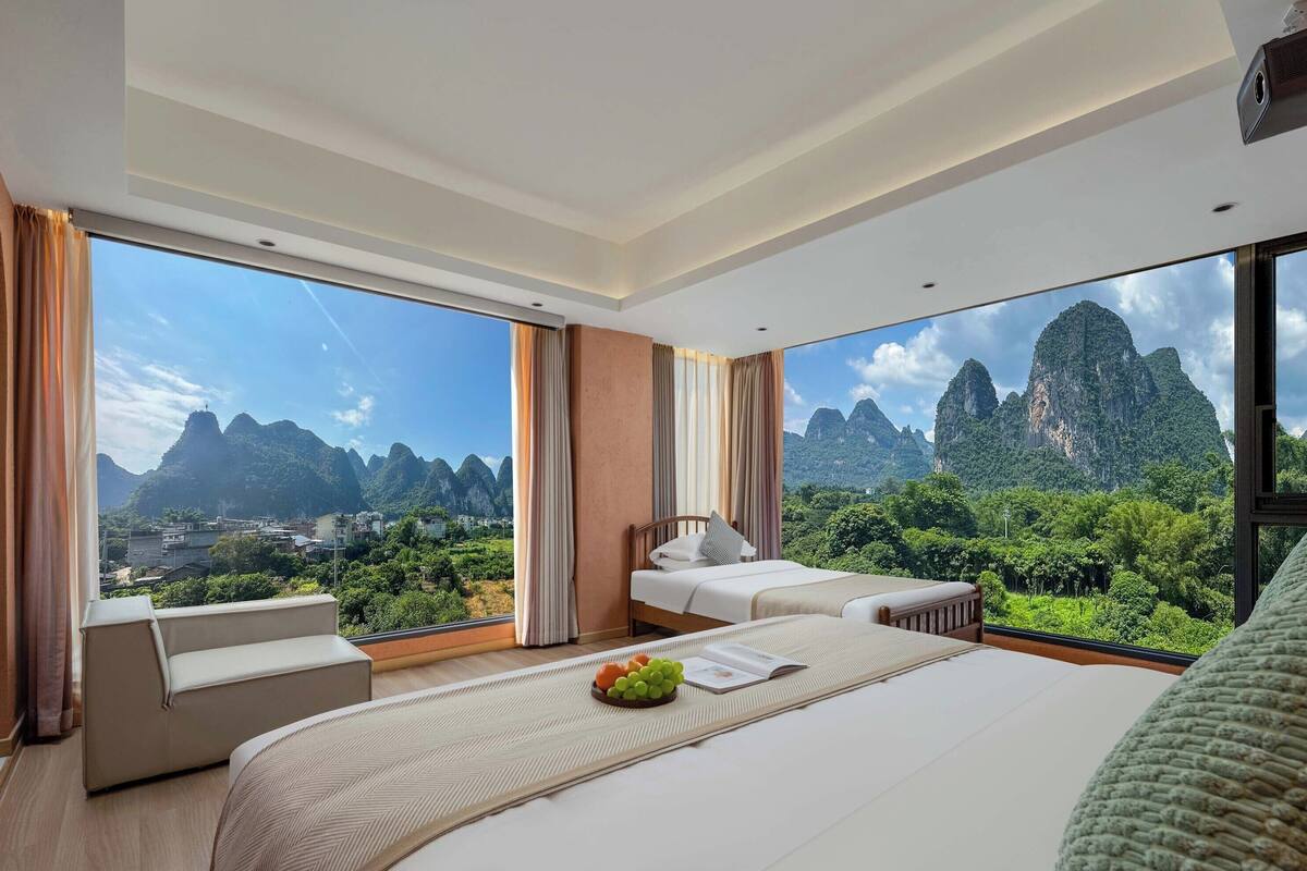 A hotel room with a large bed, a sofa, and a view of mountains.