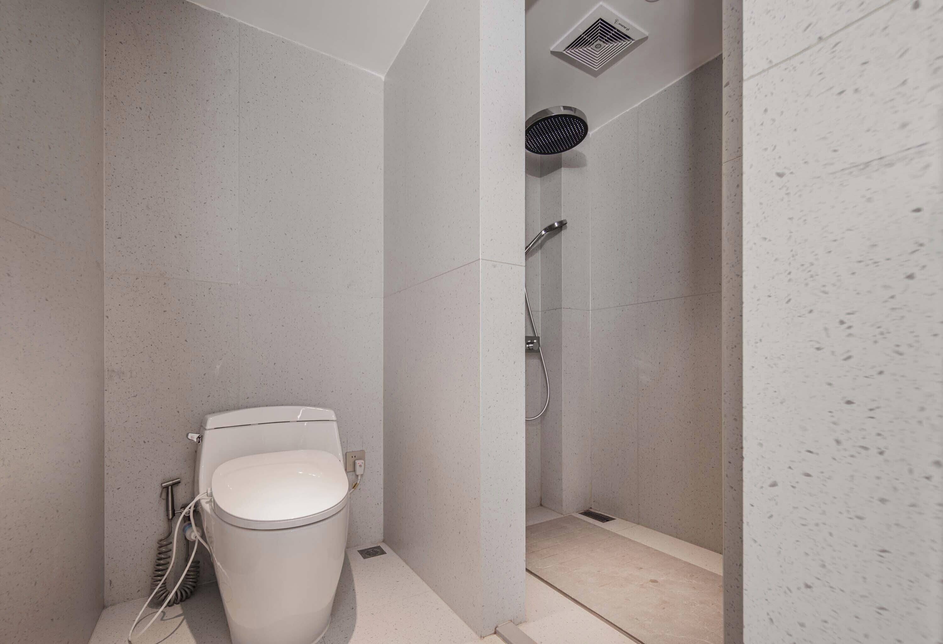 A modern bathroom with a toilet, shower, and a ventilation system.
