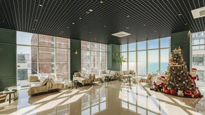 A spacious lobby with a large Christmas tree, seating areas, and large windows offering views of the city. - Hotel Costa Siheung Geobuksum (Siheung)