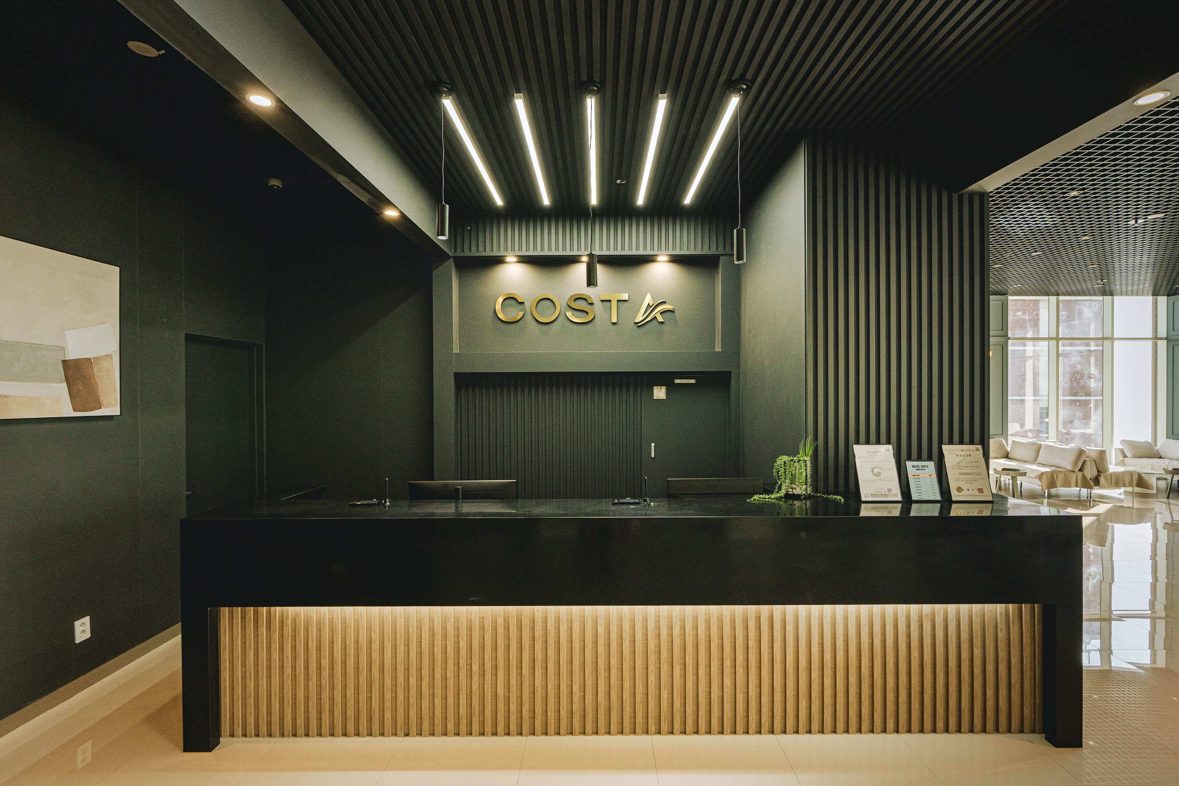 A reception desk with a modern design, featuring a dark color scheme and a sign that reads "COSTA".