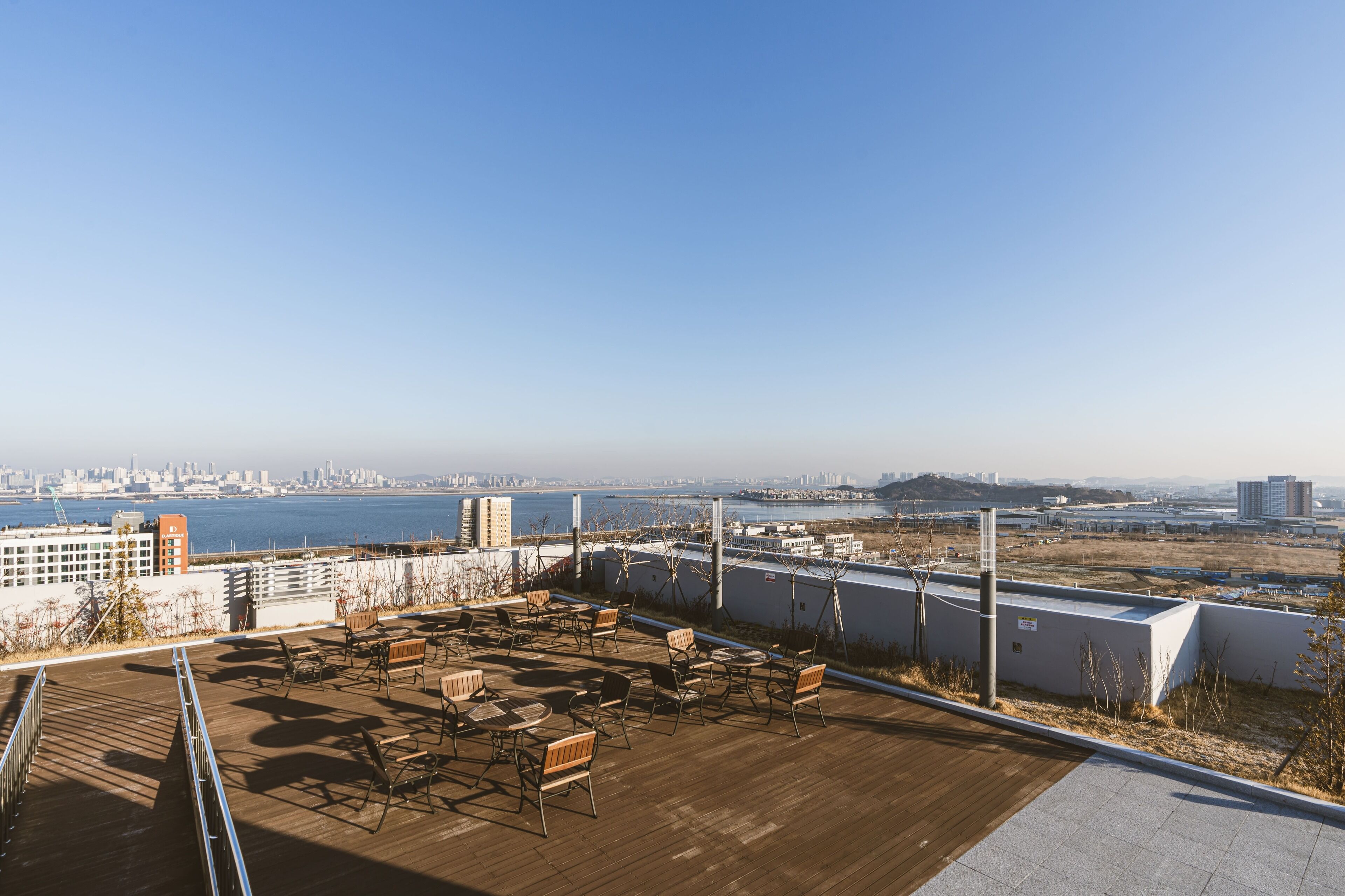 Terraza en la azotea con mobiliario exterior y vistas al horizonte de la ciudad y al agua.
