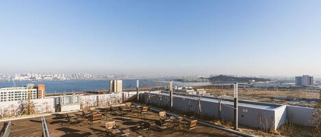 Terraza en la azotea con mobiliario exterior y vistas al horizonte de la ciudad y al agua.