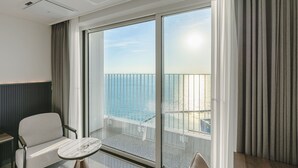 A modern hotel room with a large sliding glass door leading to a balcony with a view of the sea. - Hotel Costa Siheung Geobuksum (Siheung)