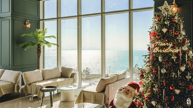 A modern living room with a large window, a Christmas tree, and a sofa. - Hotel Costa Siheung Geobuksum (Siheung)