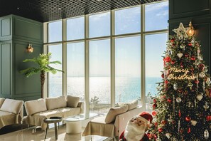 Ein modernes Wohnzimmer mit großem Fenster, einem Weihnachtsbaum und einer Couch.