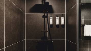 A modern shower area with a control panel, a towel rack, and toiletries.
