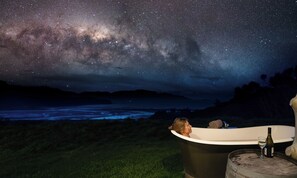 A person relaxing in a bathtub under a starry night sky with a view of the Milky Way. - Kiwi Greenie - Passive House, Golden Bay (Takaka)