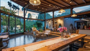 A spacious room with large windows, wooden furniture, and a long table with a lace runner. - Yangshuo 1Q84 Tree Hotel (Guilin)