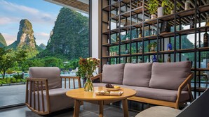 A modern interior with a sofa, chairs, a round table, and a bookshelf with plants. - Yangshuo 1Q84 Tree Hotel (Guilin)