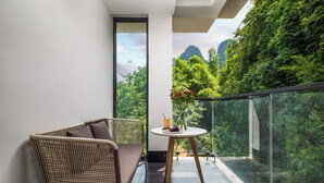 A balcony with a wicker chair and a small table with a drink and flowers. - Yangshuo 1Q84 Tree Hotel (Guilin)