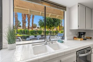 Eine moderne Küche mit großem Fenster, integriertem Grill und Kaffeemaschine.