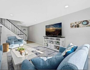 Una sala de estar moderna con sofá, mesa de centro y mueble para televisión.