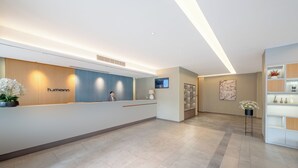 A modern reception area with a reception desk, a digital screen, and a potted plant. - Zhangjiajie Homeinn Hotel (Zhangjiajie)