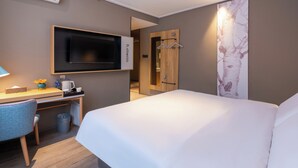 A hotel room with a bed, a desk with a chair, a TV, a coat rack, and a trash bin. - Zhangjiajie Homeinn Hotel (Zhangjiajie)