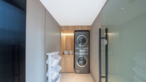 A modern laundry room with a front-loading washer and dryer, a wooden cabinet, and a glass partition. - Zhangjiajie Homeinn Hotel (Zhangjiajie)