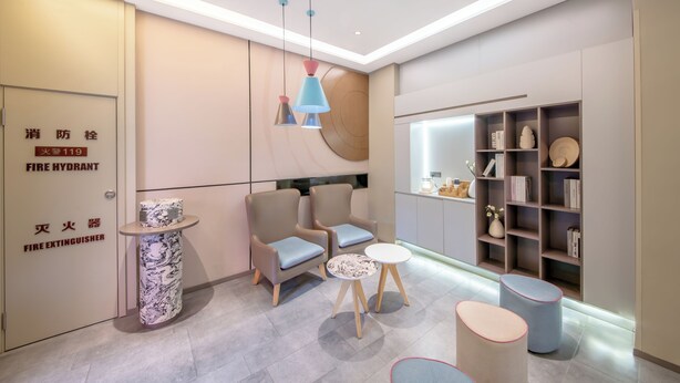 A modern waiting area with seating, a small table, and a bookshelf. - Zhangjiajie Homeinn Hotel (Zhangjiajie)