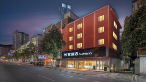 A modern hotel with a red facade, multiple floors, and illuminated windows. - Zhangjiajie Homeinn Hotel (Zhangjiajie)