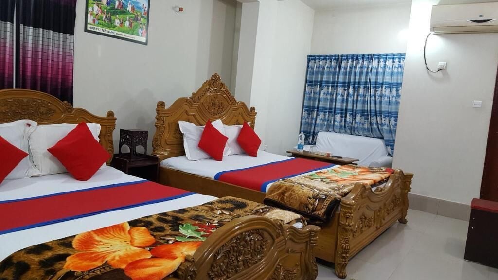 Habitación de hotel con dos camas de madera, cada una con ropa de cama roja y blanca, y una colcha de estampado floral.