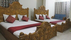Dos camas de madera con cabeceras decoradas, sábanas blancas y almohadas rojas y rosas.