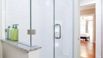 Ein modernes Badezimmer mit Duschkabine aus Glas, einer Arbeitsplatte aus Granit und einem sichtbaren Waschtisch.
