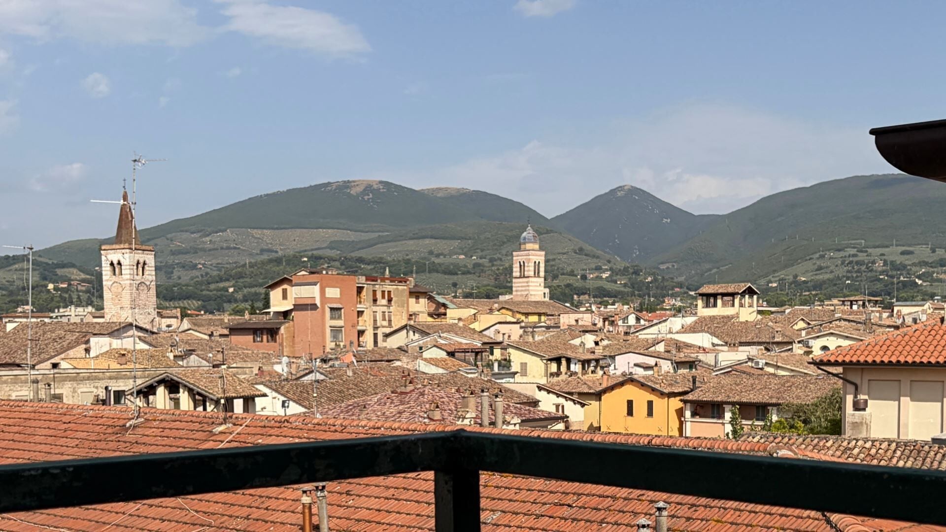 A town with historic buildings, a prominent church tower, and a mountain backdrop.