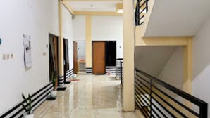 A corridor with a tiled floor, a black railing on the right, and a door at the end. - Rumi Hotel (Malang)