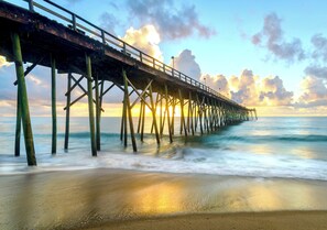 Un muelle que se adentra en el océano, con un atardecer de fondo.
