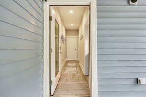 A narrow hallway with a wooden floor, a doormat, and a door at the end. - 2 Mi to Boardwalk! Coastal Carolina Beach Hideaway (Carolina Beach)