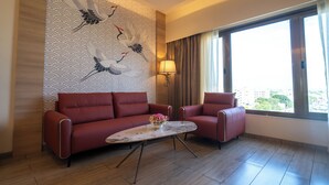 A modern hotel room with a red sofa, a marble coffee table, and a wall mural. - Pride Elite Chhatrapati Sambhaji Nagar (Chhatrapati Sambhajinagar)