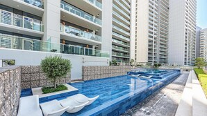 A modern hotel with a rooftop pool, multiple balconies, and a stone wall. - Stayshort - 1 Bed in Business Bay Sleeps 2 With City View (Dubai)