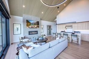 A spacious living area with a large sofa, a fireplace, and a kitchen with bar stools. - Labor Day Sale - Limited Time Offer, Save up to 30% (Francis)