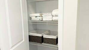 A closet with shelves and baskets, containing folded towels and storage boxes. - Clean, Cozy, Comfy & Modern (Calgary)